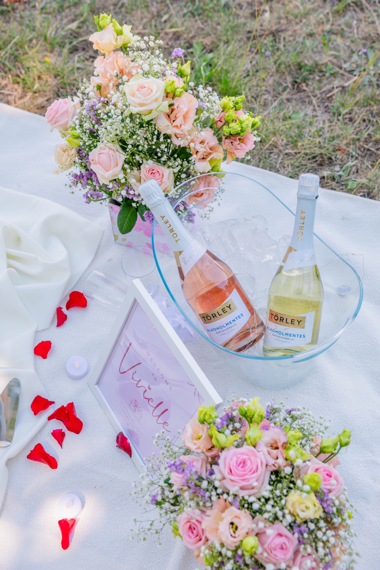 Rosé and sparkling refreshments with pastel florals and welcome signage — luxury picnic refreshment styling by Vivielle Events