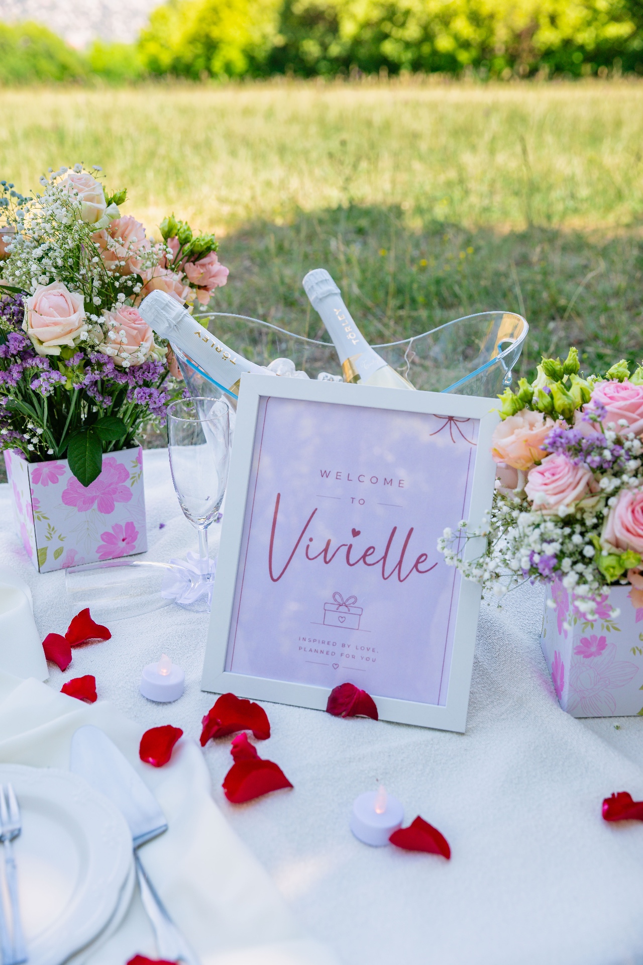 Personalised Vivielle welcome sign with Törley champagne and pastel florals — luxury proposal picnic Budapest