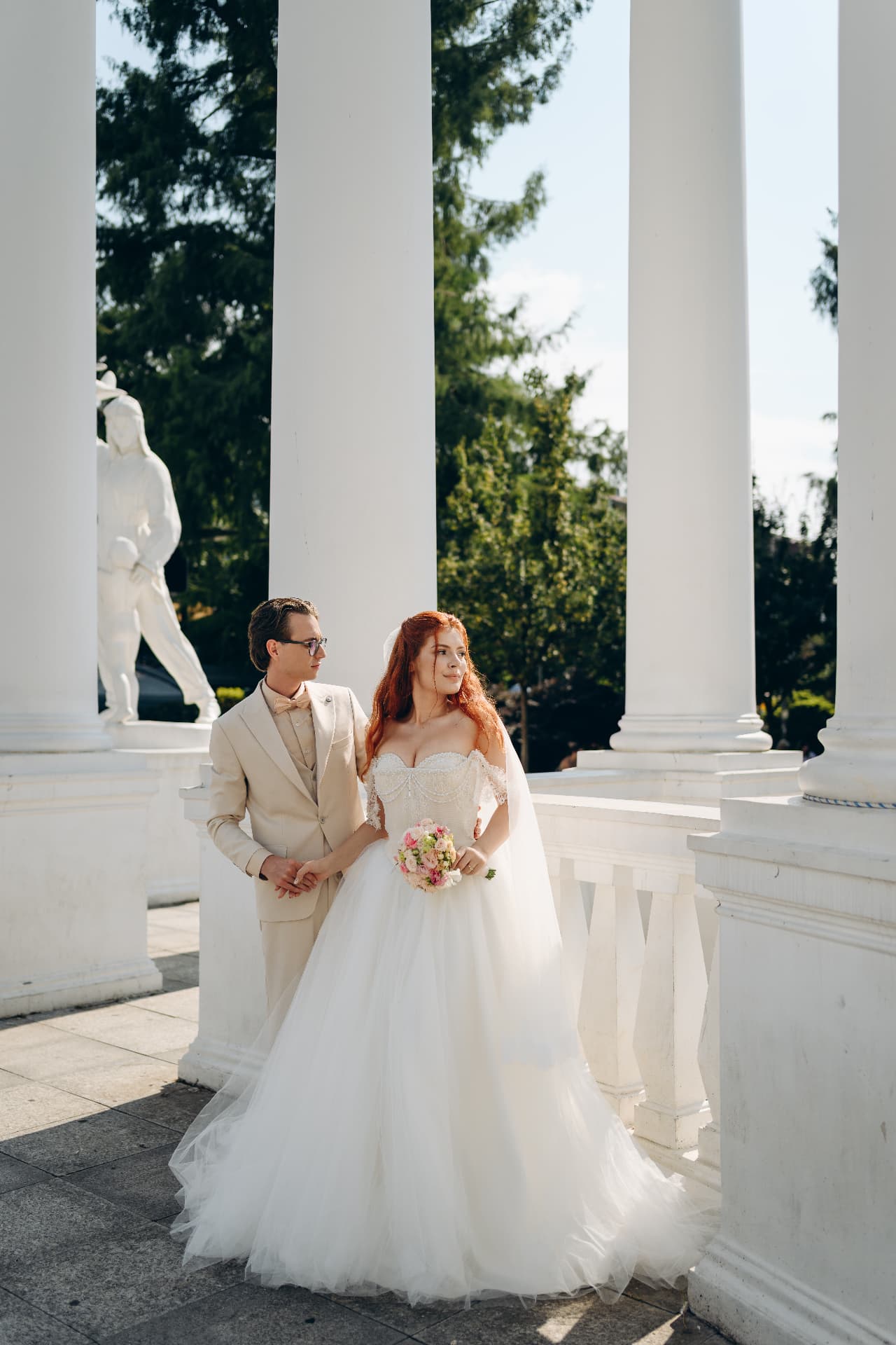 Newlywed couple posing between elegant white columns in Budapest