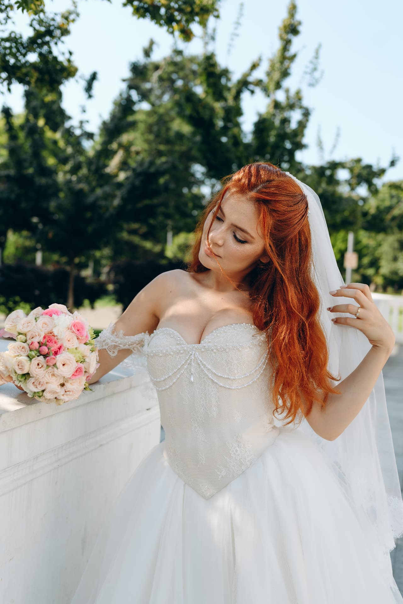 Romantic bridal portrait in a pearl corset gown with veil and blush rose bouquet
