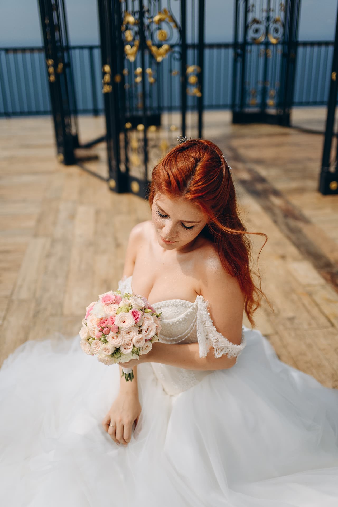 Bride seated in a tulle ballgown holding a detailed blush and pink garden rose bouquet