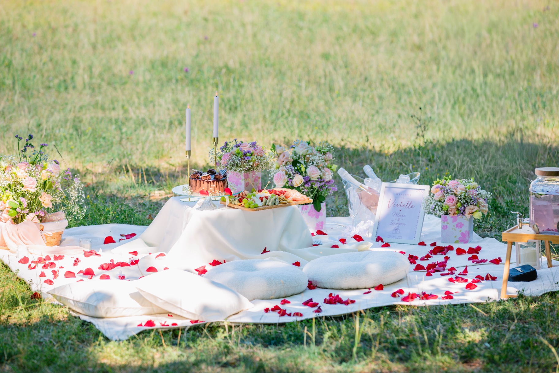 Luxury meadow proposal picnic with rose petals, floral arrangements and grazing table — Vivielle Events Budapest