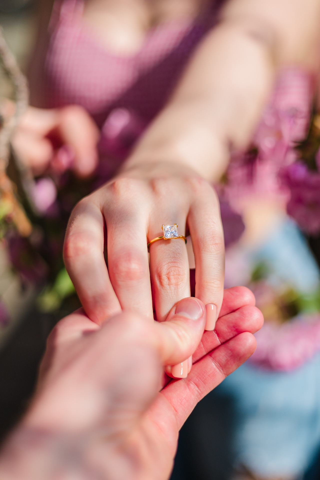 Engagement ring on bride's hand surrounded by florals