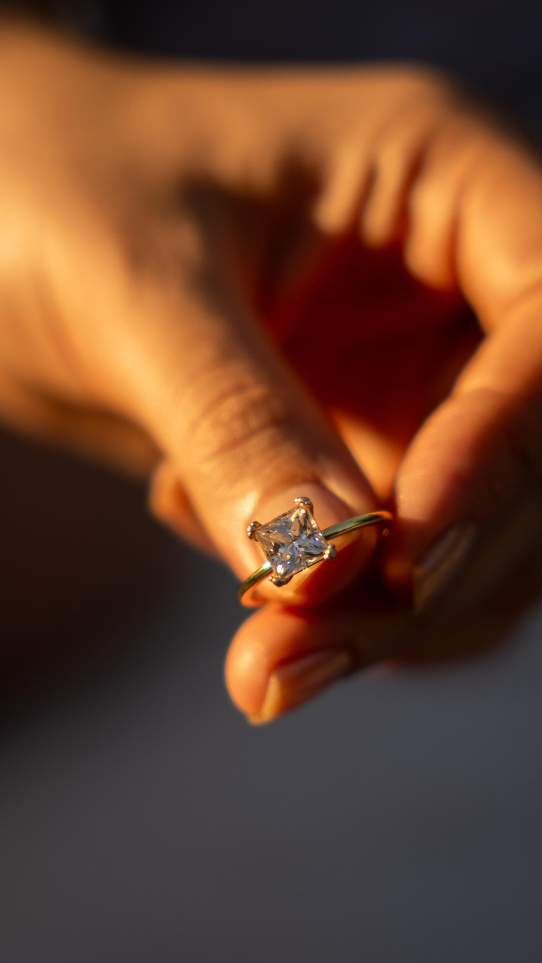 Close-up of a square-cut engagement ring held in warm golden light