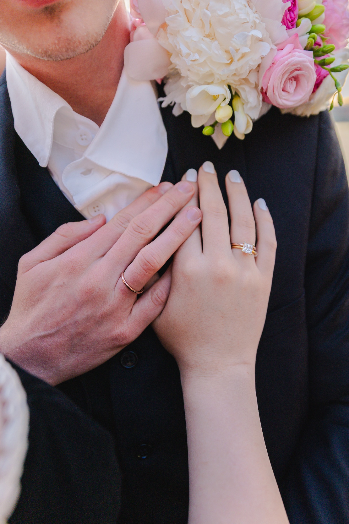 Close-up of engagement ring and wedding bands with bridal bouquet
