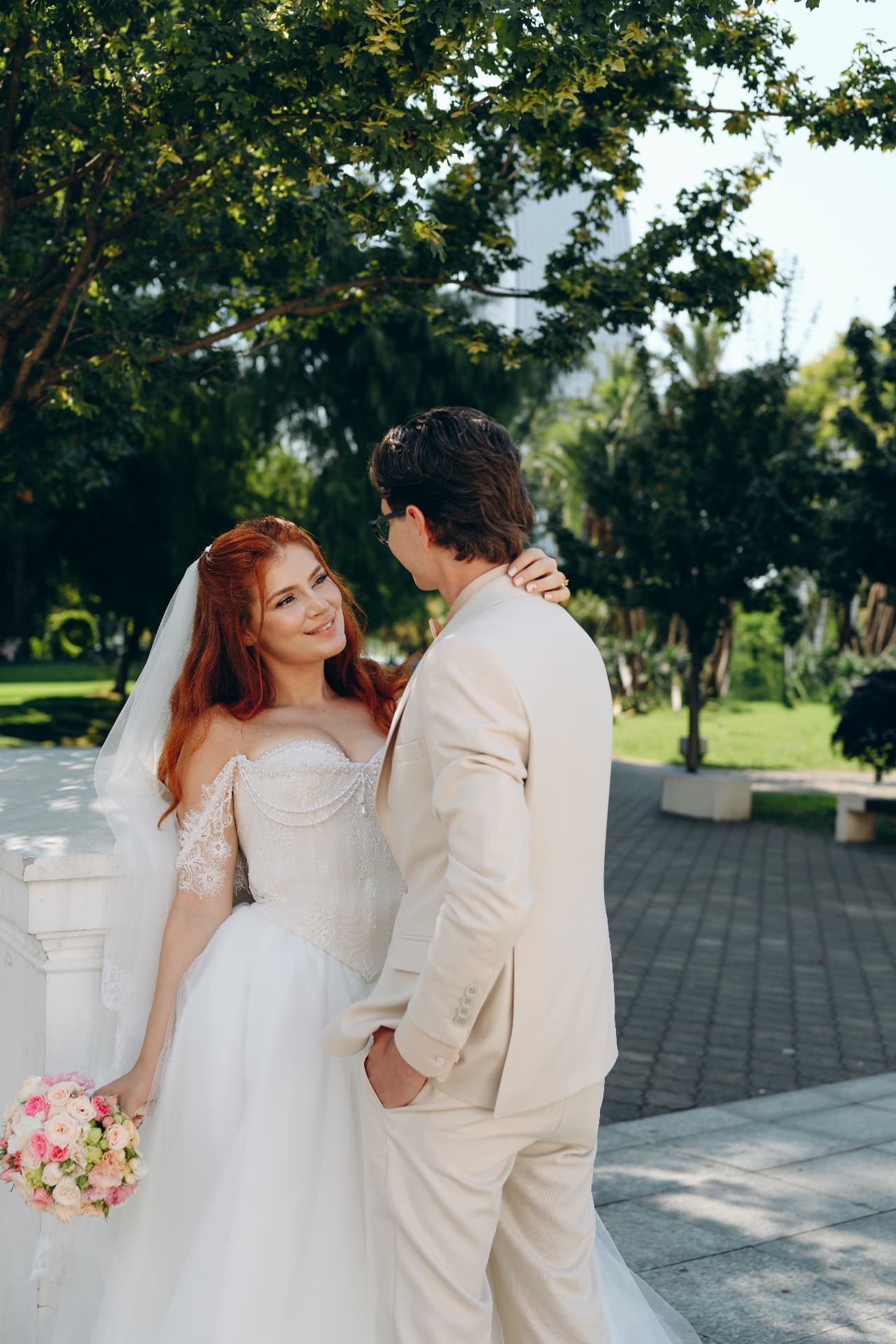 Bride and groom looking at each other in a garden with a blush rose bouquet