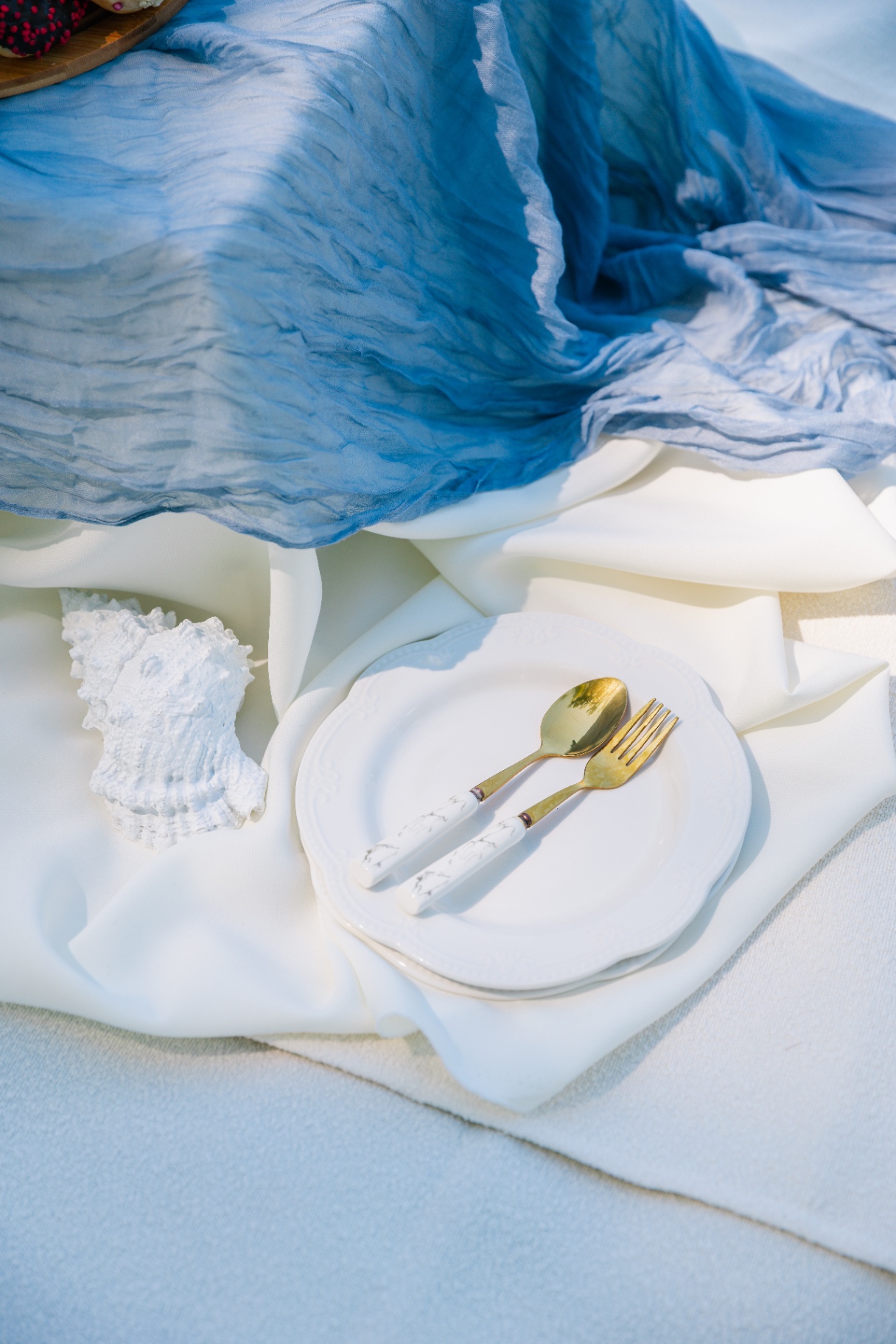 Coastal luxury picnic styling Budapest with blue gauze runner, white linens and gold cutlery
