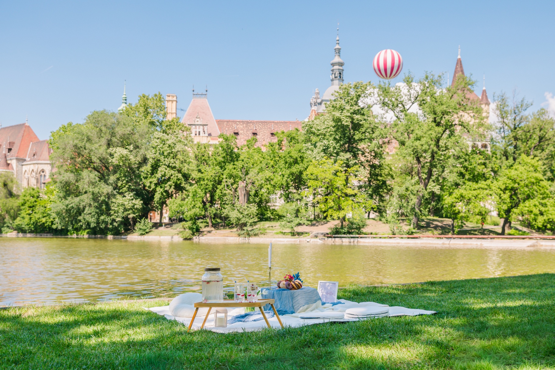Premium lakeside luxury picnic in Budapest with blue gauze runner overlooking Vajdahunyad Castle
