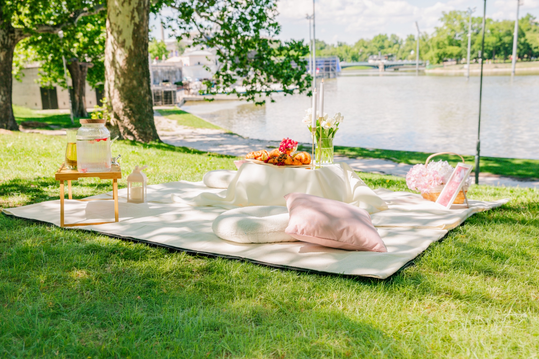 Riverside luxury picnic styling in Budapest with pink cushion, lantern and floral basket