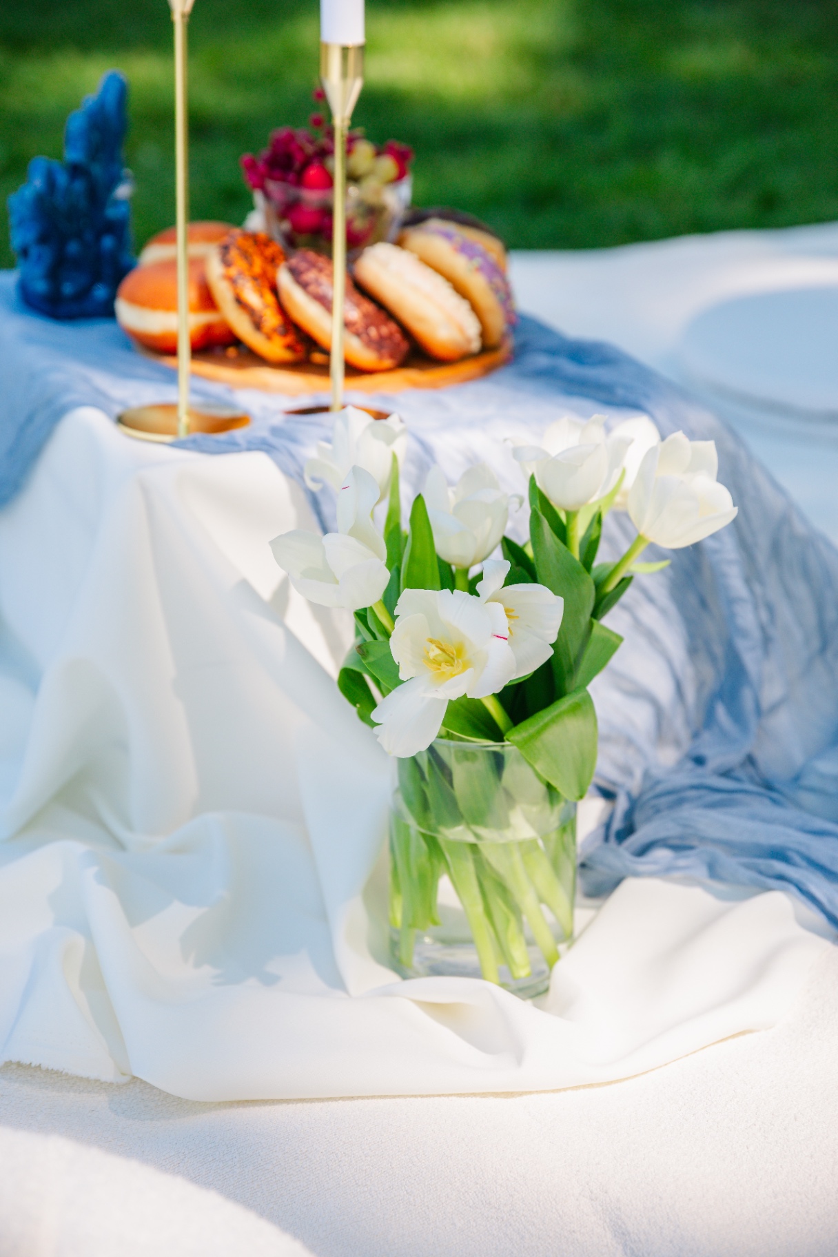 Luxury picnic Budapest tablescape with white tulips, blue gauze runner and donut platter
